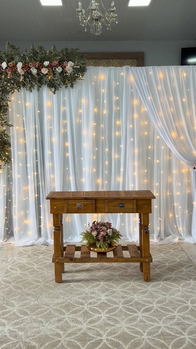 Wooden table in front of a white curtain backdrop with glowing fairy lights.
