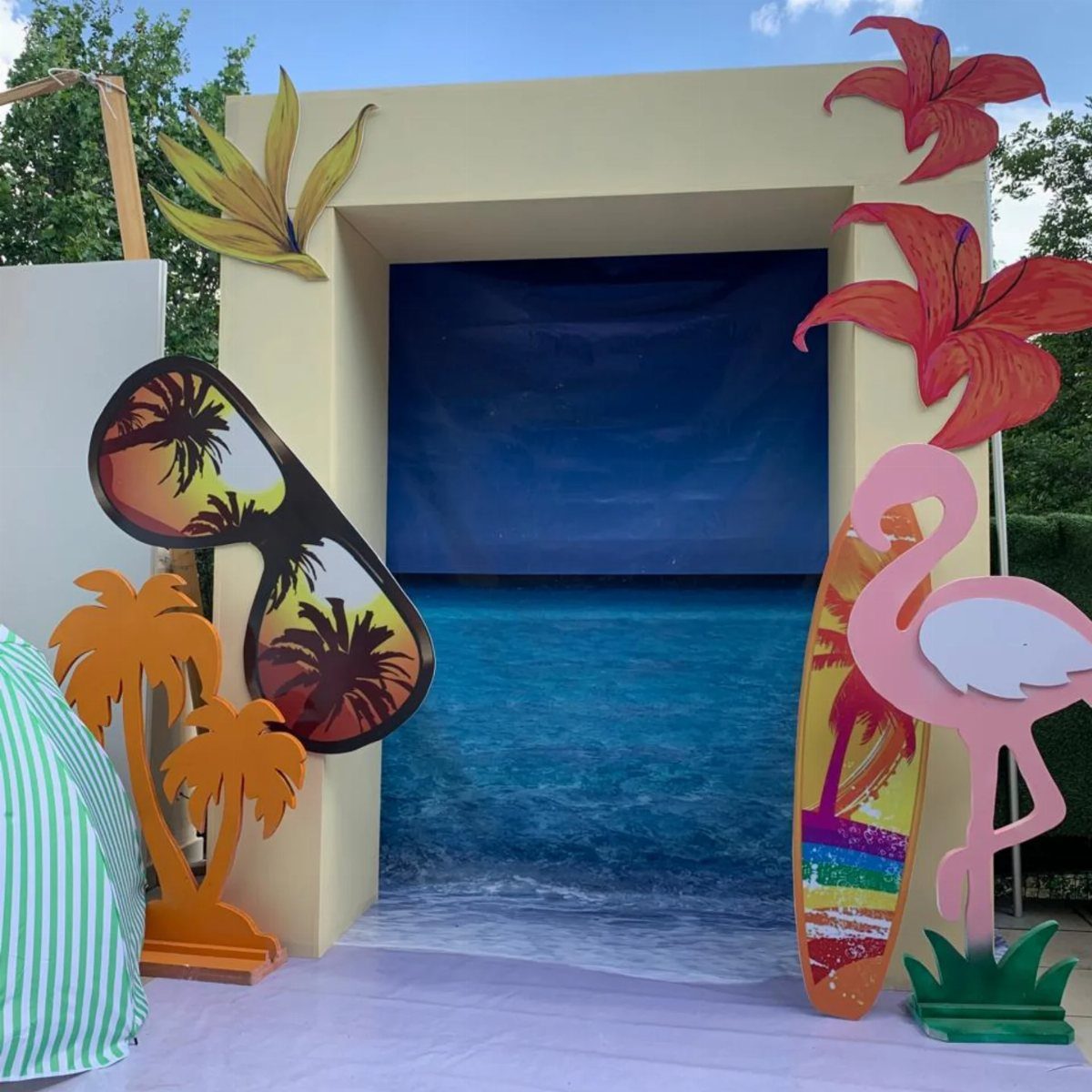 Large colorful cutouts of sunglasses, palm trees, a flamingo, and a surfboard for a photo booth.