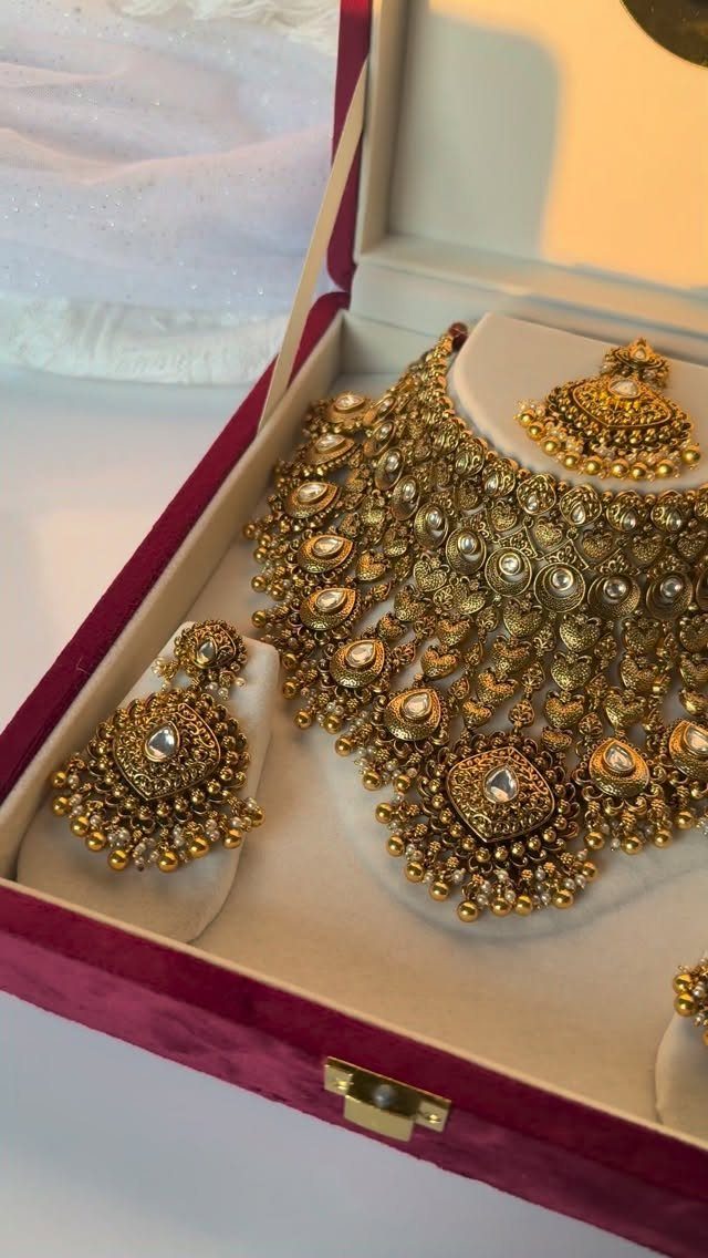 A gold bridal jewelry set with a necklace and earrings inside a velvet box.