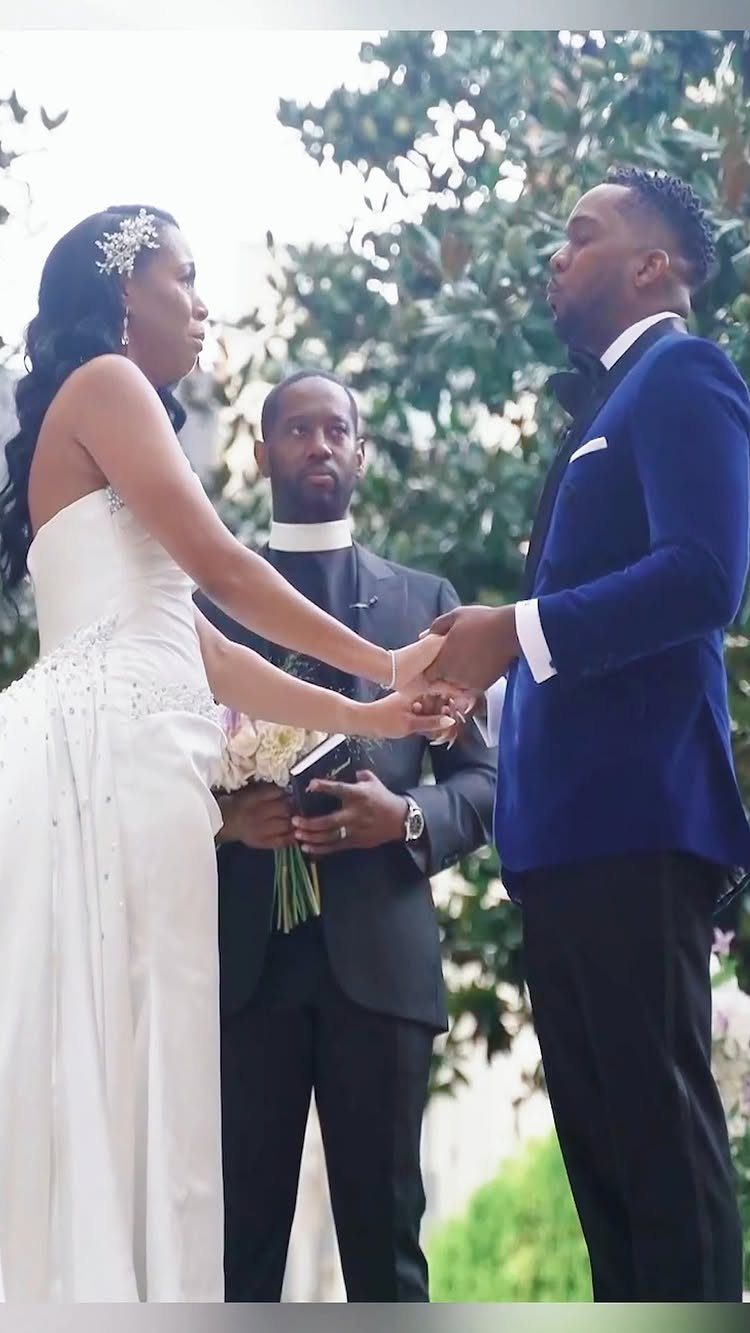 Bride and groom holding hands facing each other during their wedding ceremony outdoors.