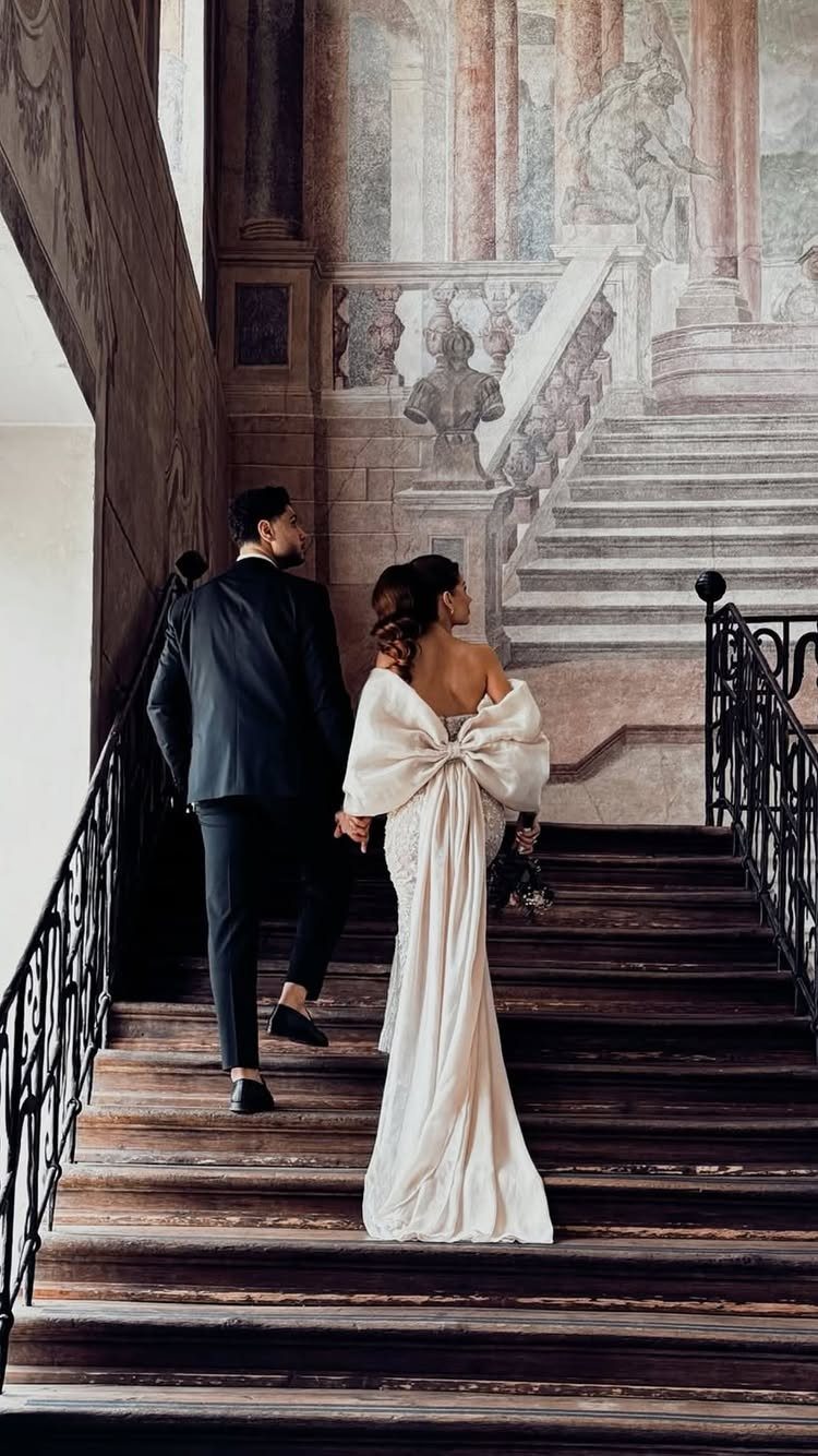 A bride and groom walking up a wooden staircase towards a large wall mural.