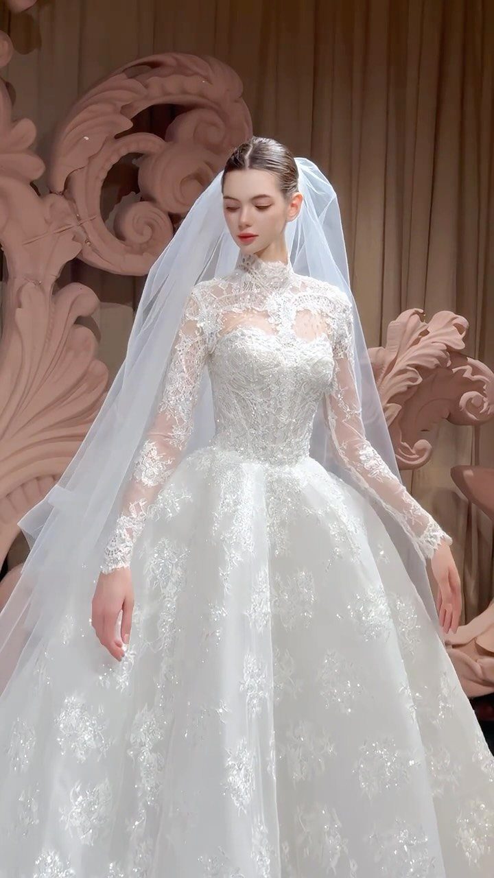 Classy Wedding Dress: 7 Styles That Photograph Beautifully 3 Woman in a white long-sleeved lace wedding gown with a high neck and voluminous skirt.
