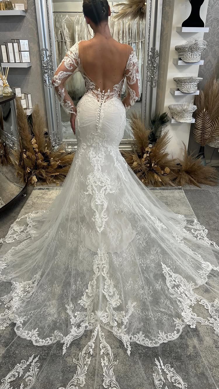 Classy Wedding Dress: 7 Styles That Photograph Beautifully 1 Woman wearing a white lace mermaid silhouette wedding dress with a long, intricate lace train.