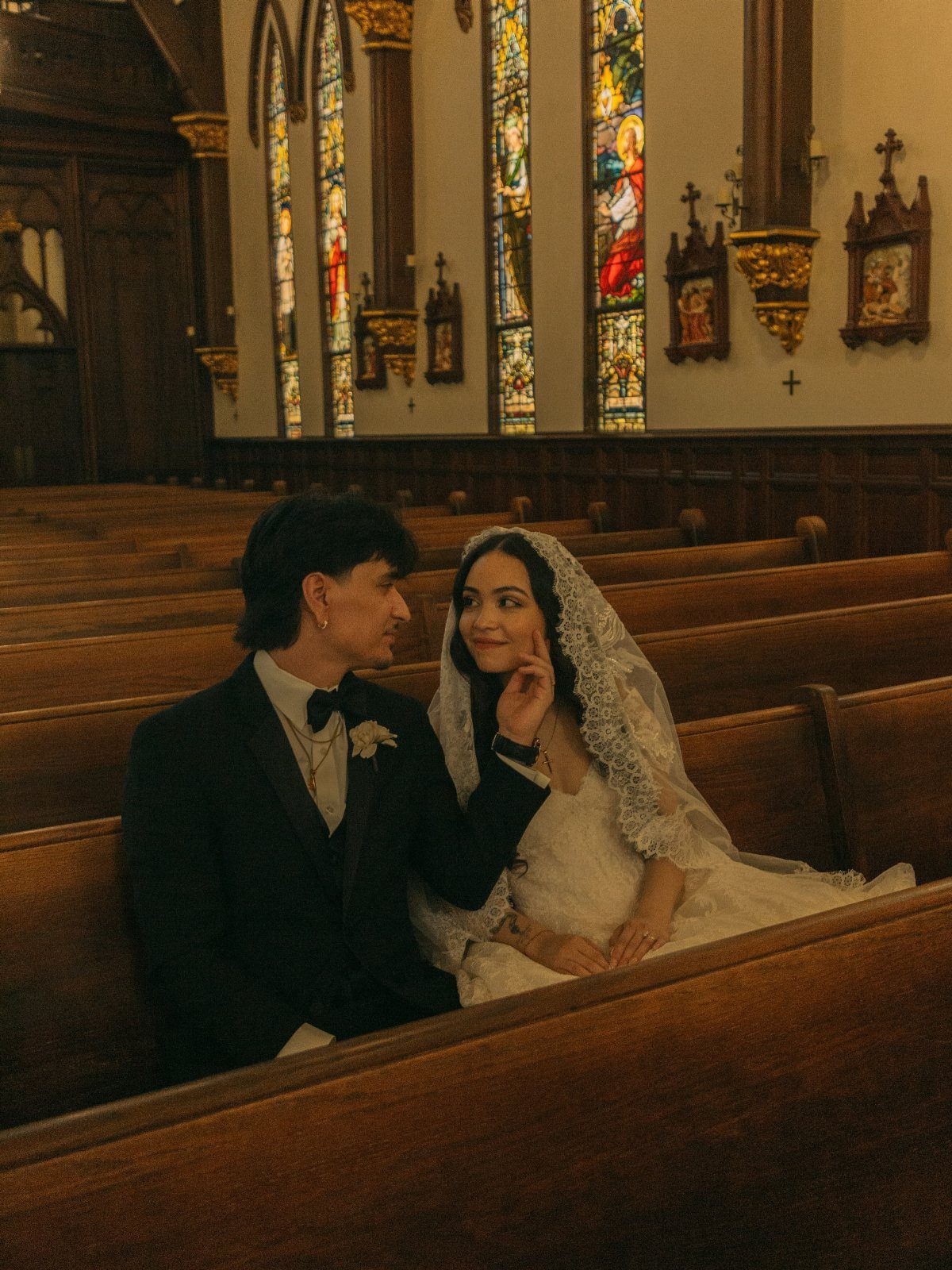 17 Couple Pictures for Your Wedding That Feel Real, Not Posed 15 A bride and groom sit in a church pew, gazing lovingly at one another.