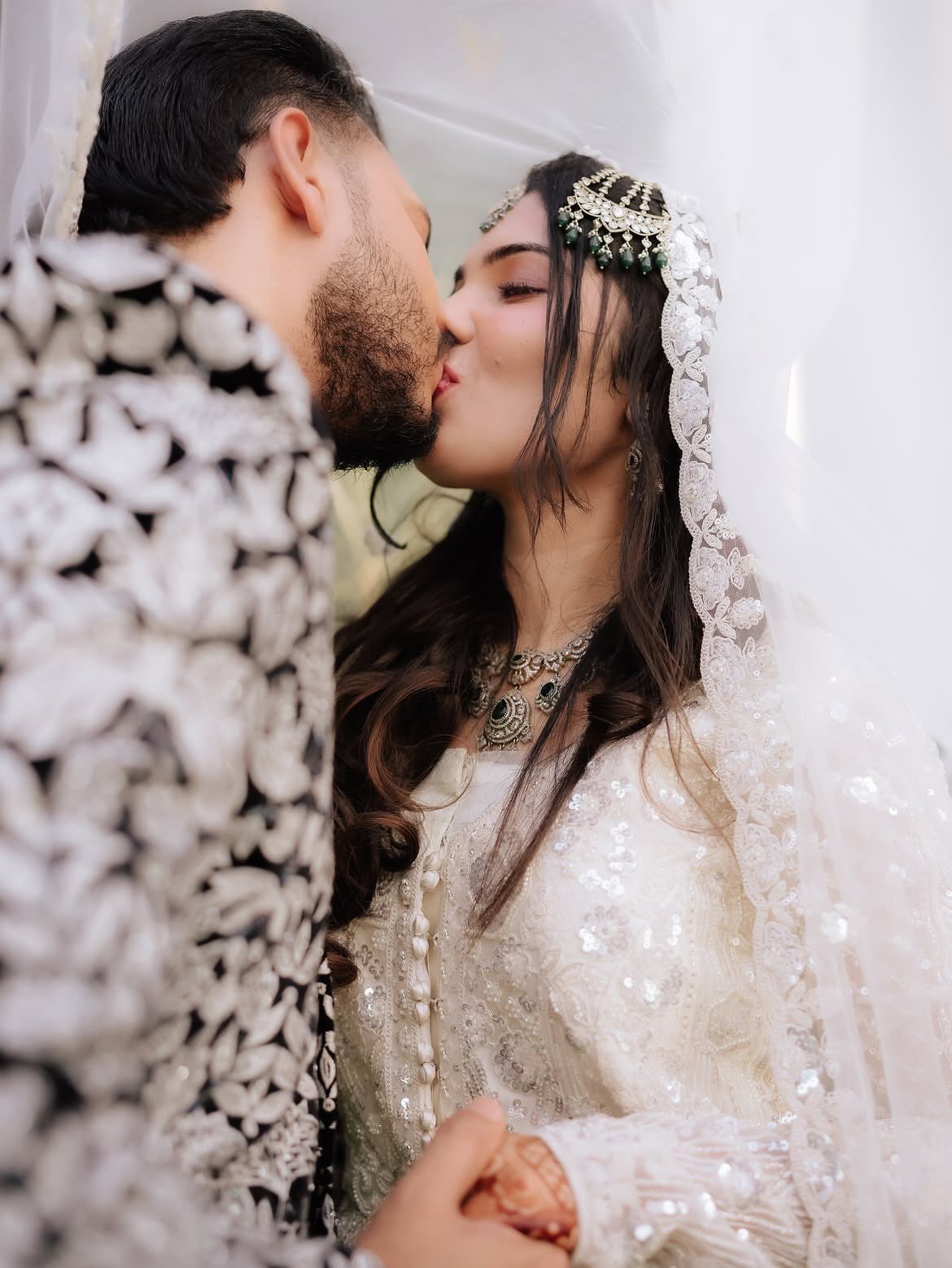 17 Couple Pictures for Your Wedding That Feel Real, Not Posed 6 A bride and groom in traditional attire sharing an intimate kiss.