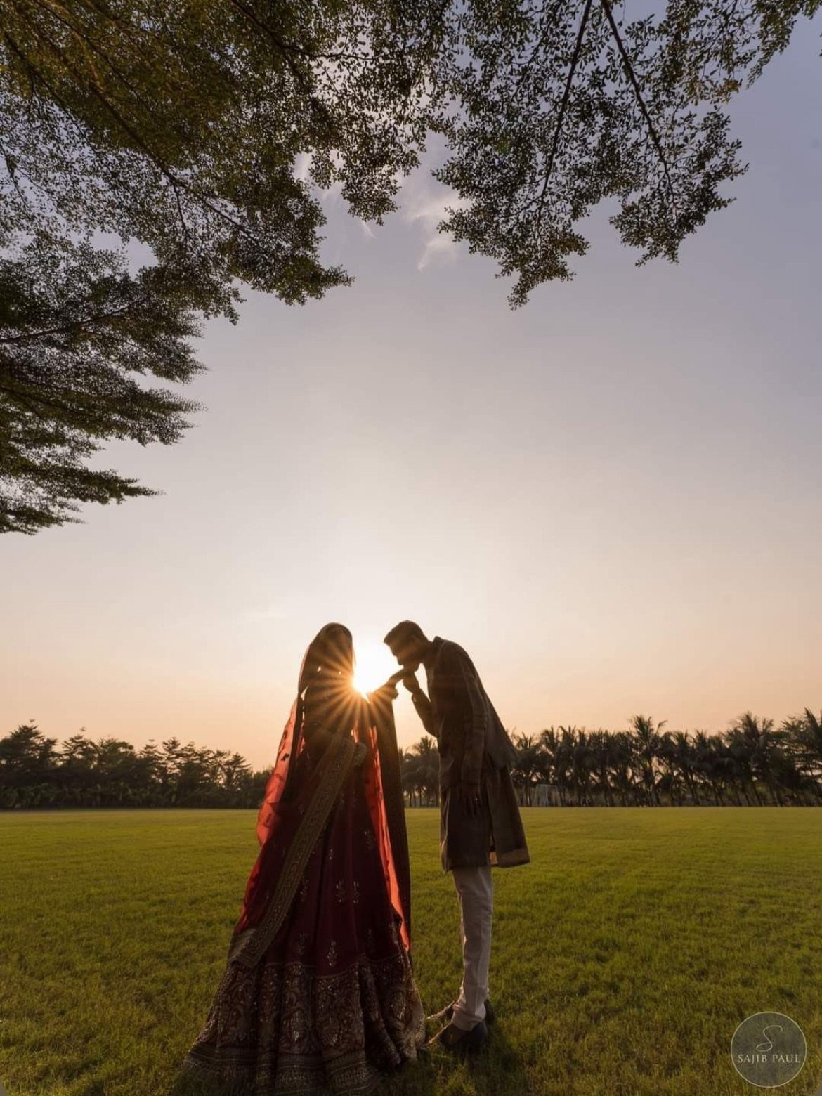 17 Couple Pictures for Your Wedding That Feel Real, Not Posed 9 Silhouette of a couple holding hands in a field against a bright sunset sky.