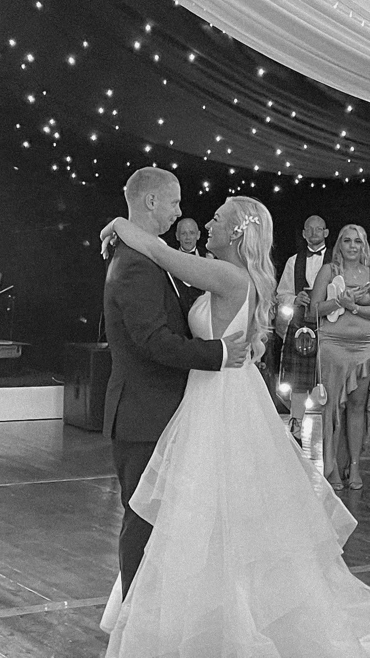 17 Couple Pictures for Your Wedding That Feel Real, Not Posed 13 A bride and groom dancing closely together in a ballroom under twinkling lights.