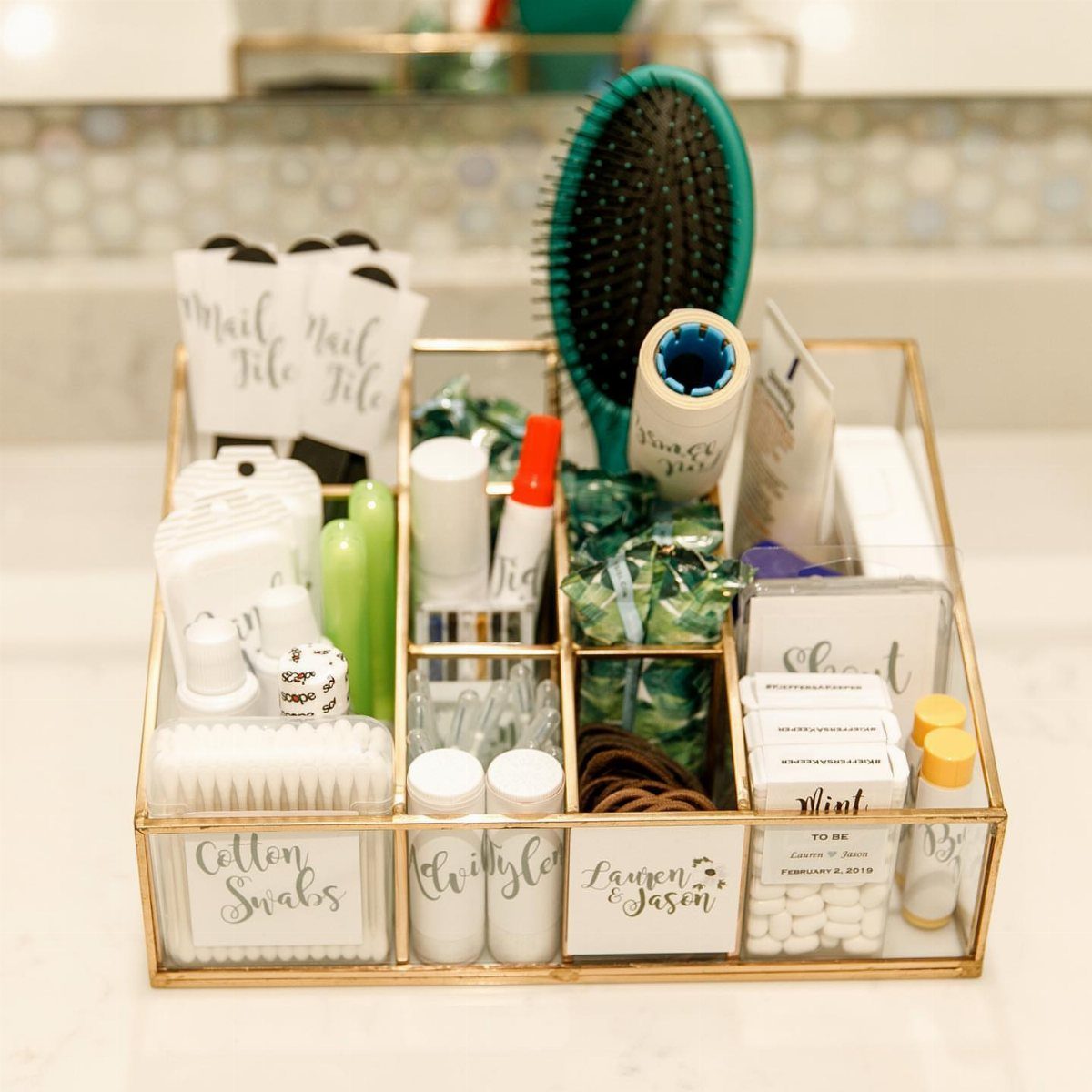 7 Cute Wedding Ideas for Guests, Photos and Reception Fun 1 A gold and glass tray containing various wedding guest bathroom toiletries and essentials.