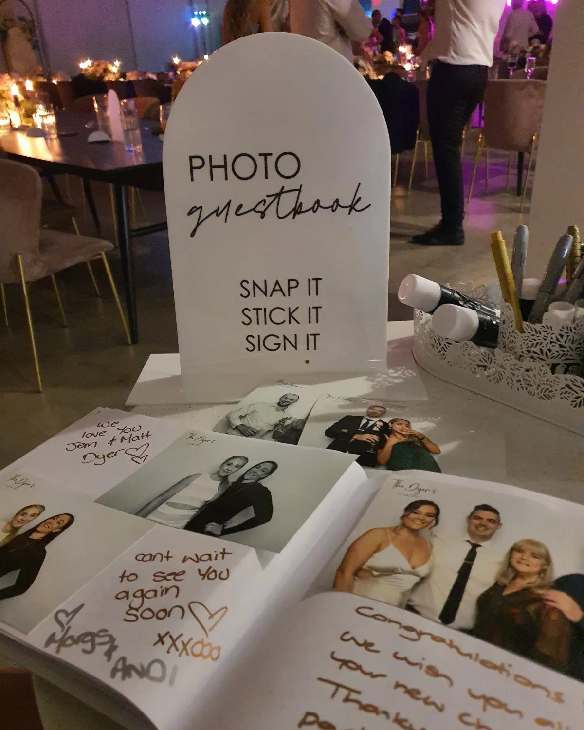 7 Cute Wedding Ideas for Guests, Photos and Reception Fun 2 A white photo guestbook sign next to an open book containing instant photos and handwritten notes.