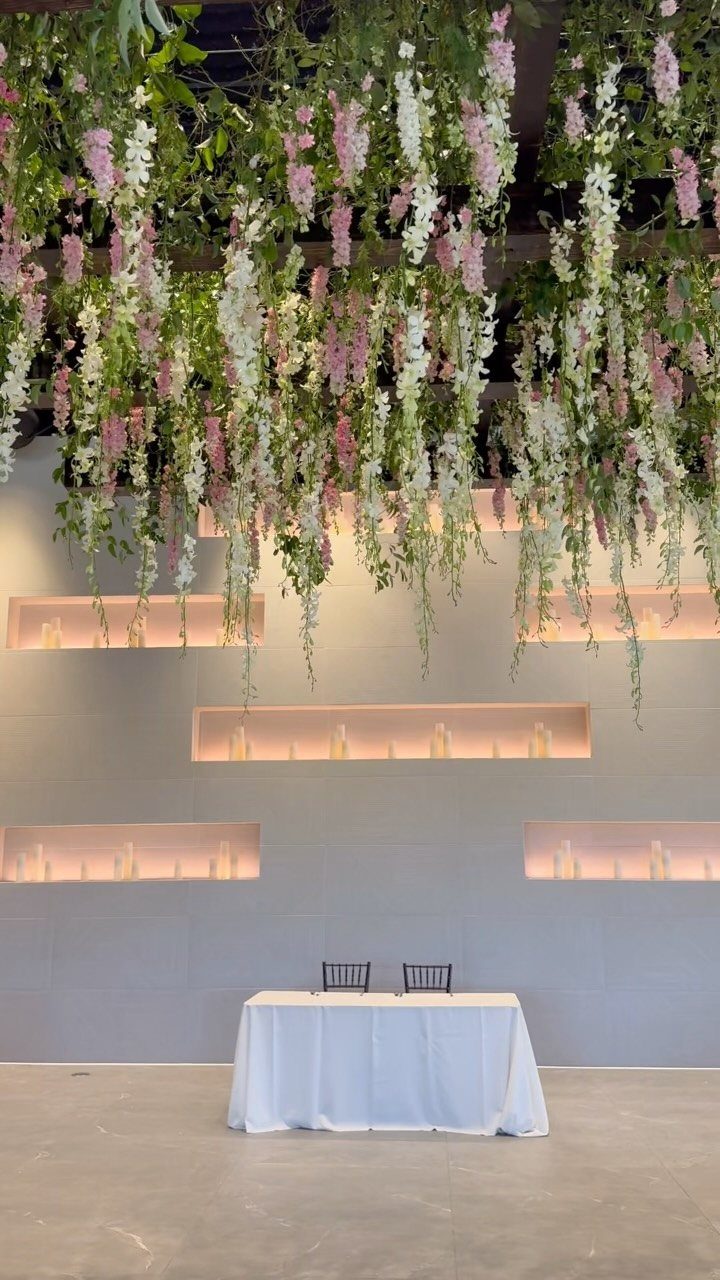 Pink and white floral arrangements hanging from the ceiling above a wedding table.