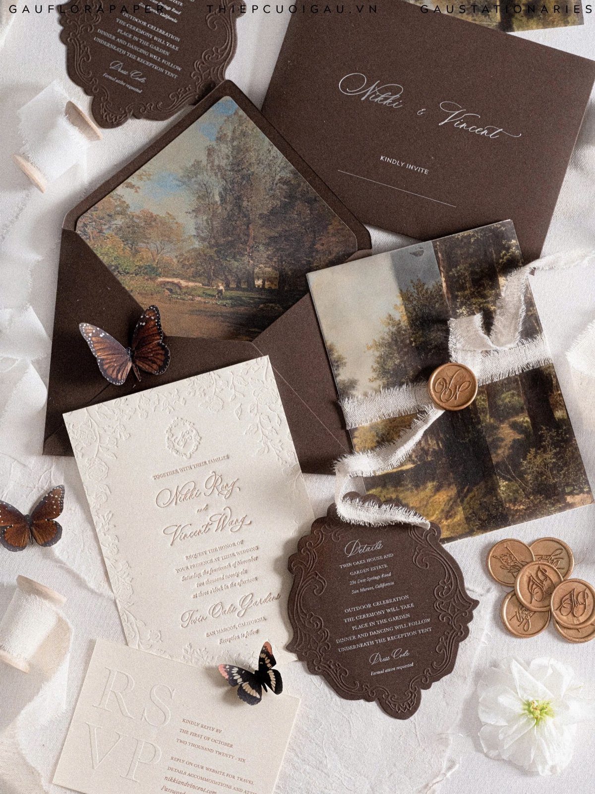 11 Forest Theme Wedding Ideas for a Natural Woodland Ceremony 7 Elegant forest-themed wedding invitations with landscape illustrations, butterflies, and wax seals on white fabric.