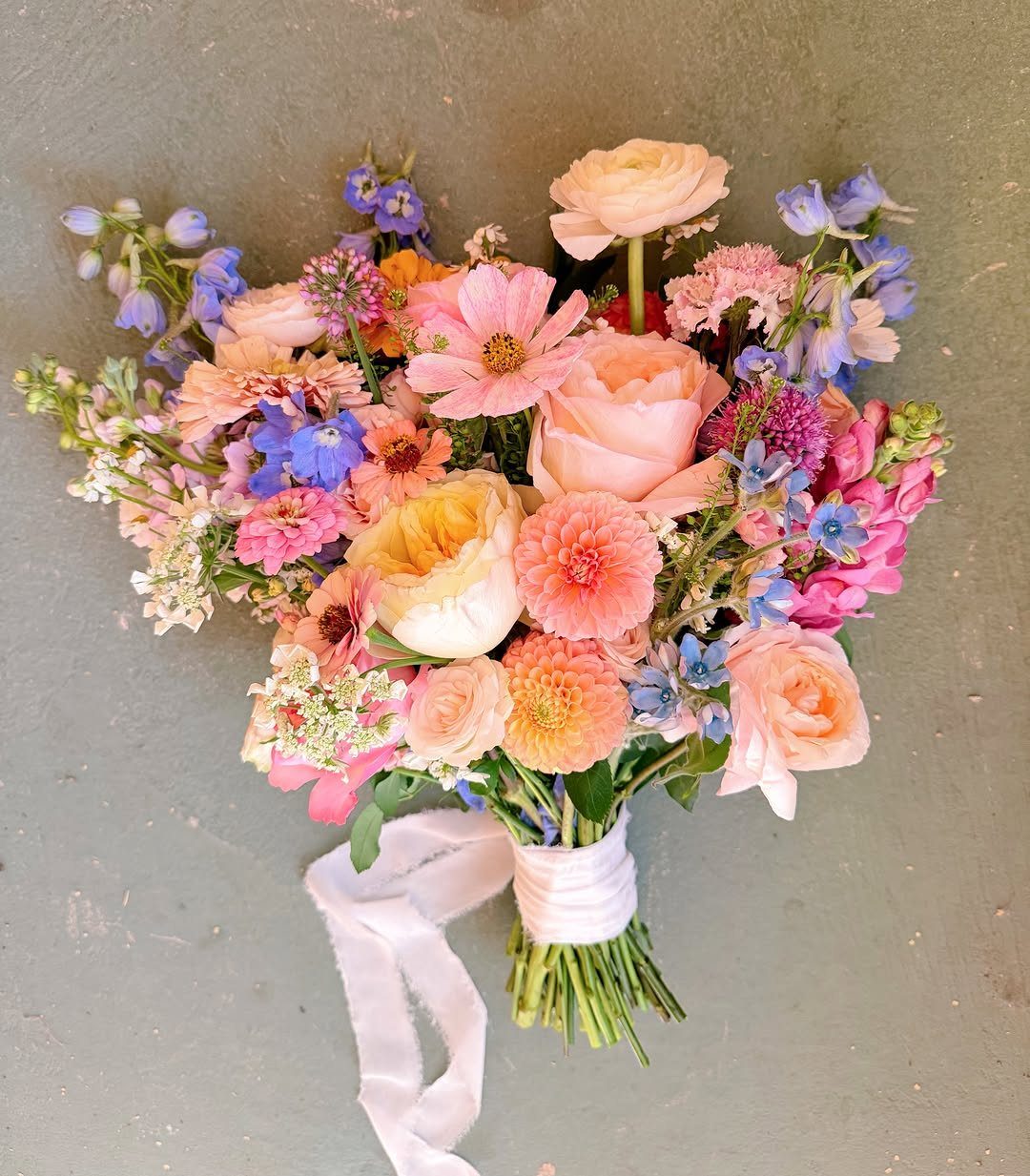 11 Forest Theme Wedding Ideas for a Natural Woodland Ceremony 4 A colorful wildflower bouquet with pink, peach, and blue blossoms tied with a white ribbon.