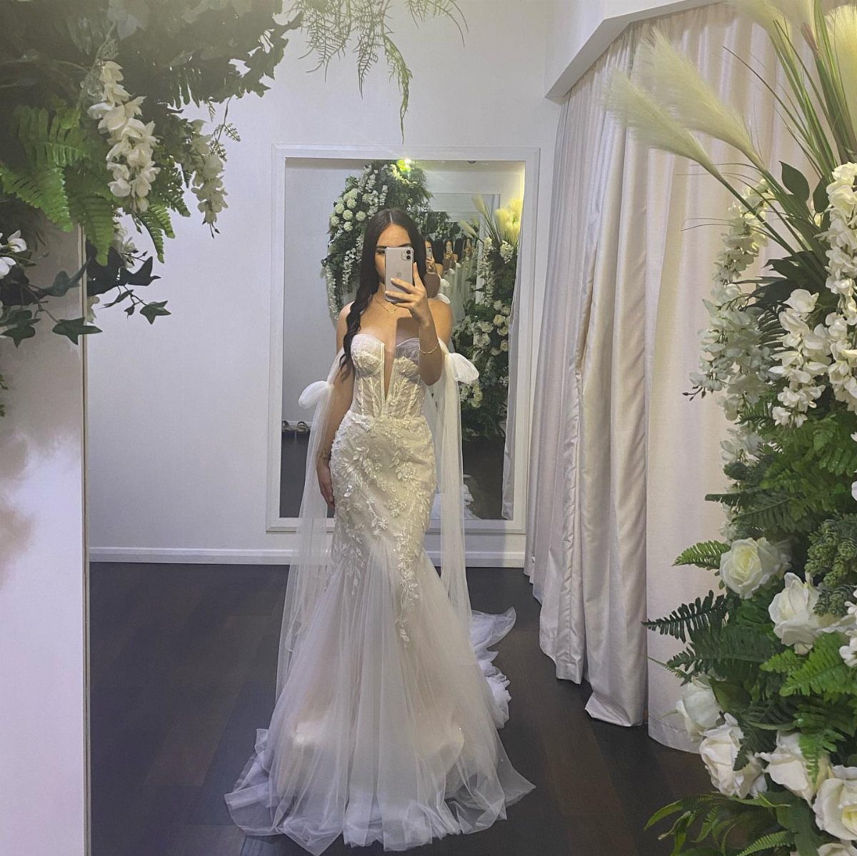 Woman in a white lace wedding dress with a corset bodice posing in a mirror.
