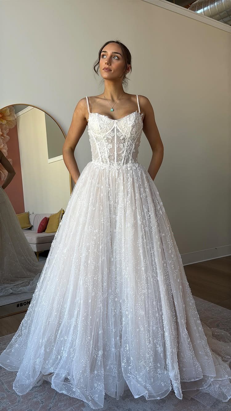 Woman in a white A-line wedding dress with a floral lace corset bodice and sparkling tulle skirt.