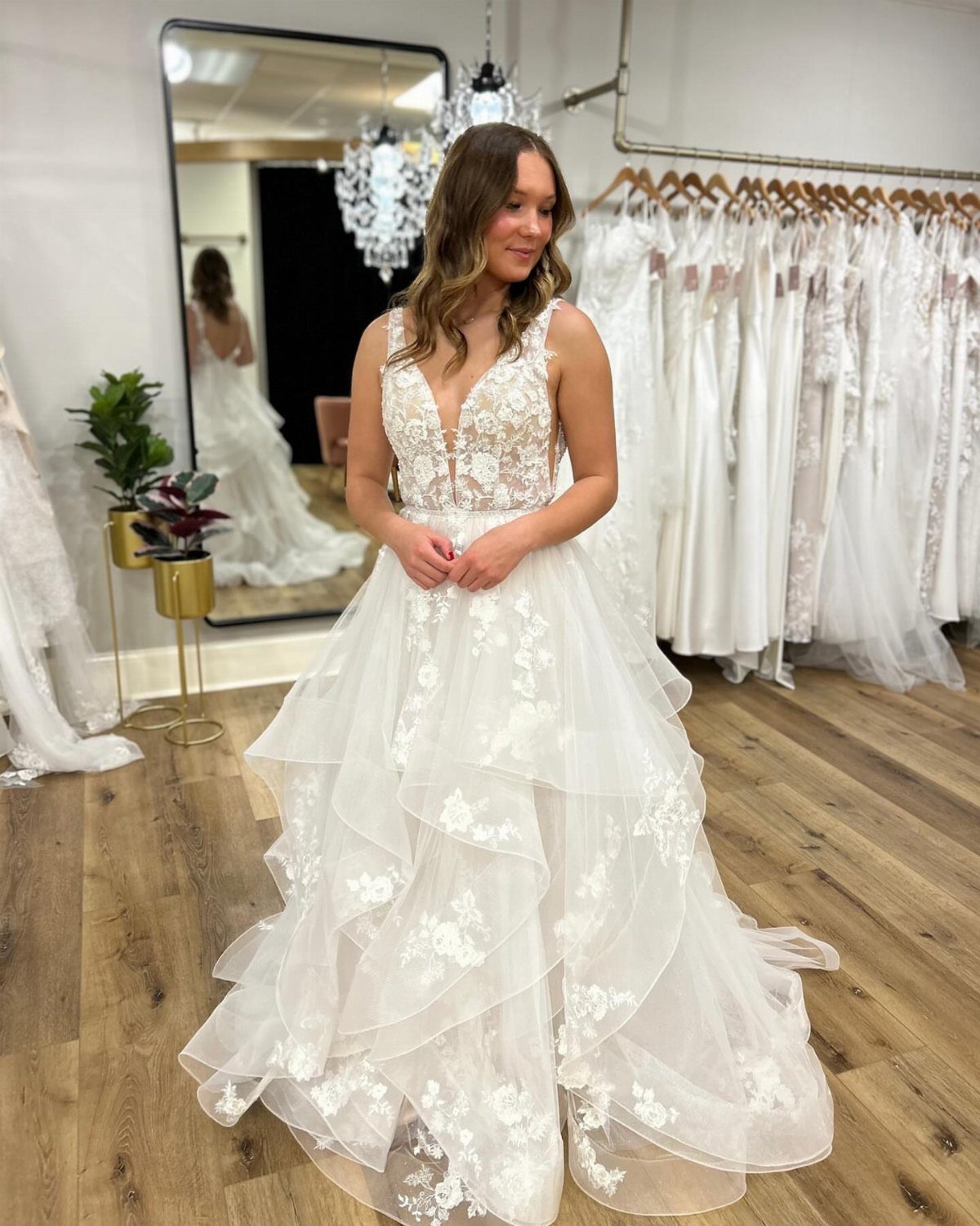 Woman posing in a white wedding dress with a lace bodice and ruffled skirt.