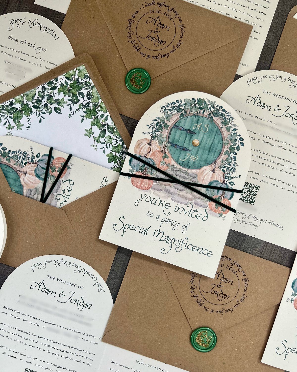 Arched wedding invitations with botanical illustrations and calligraphy scattered among kraft paper envelopes with wax seals.