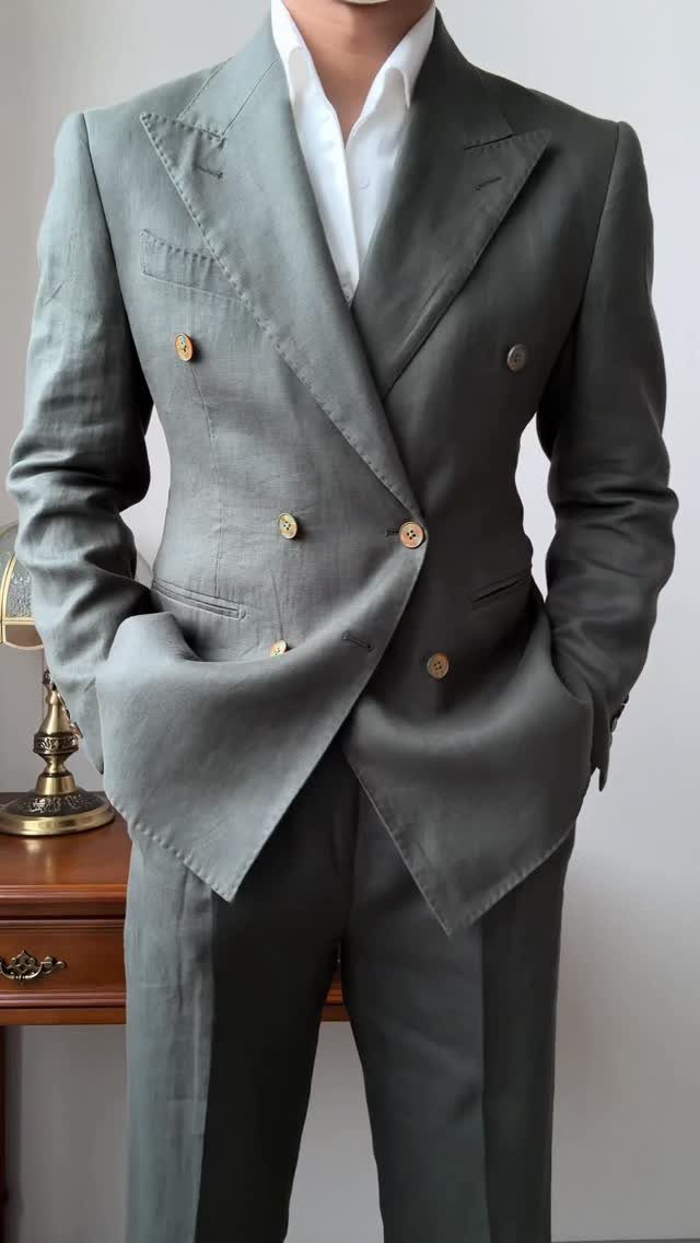 A man wearing a stylish olive green double-breasted linen suit with gold buttons and a white shirt.