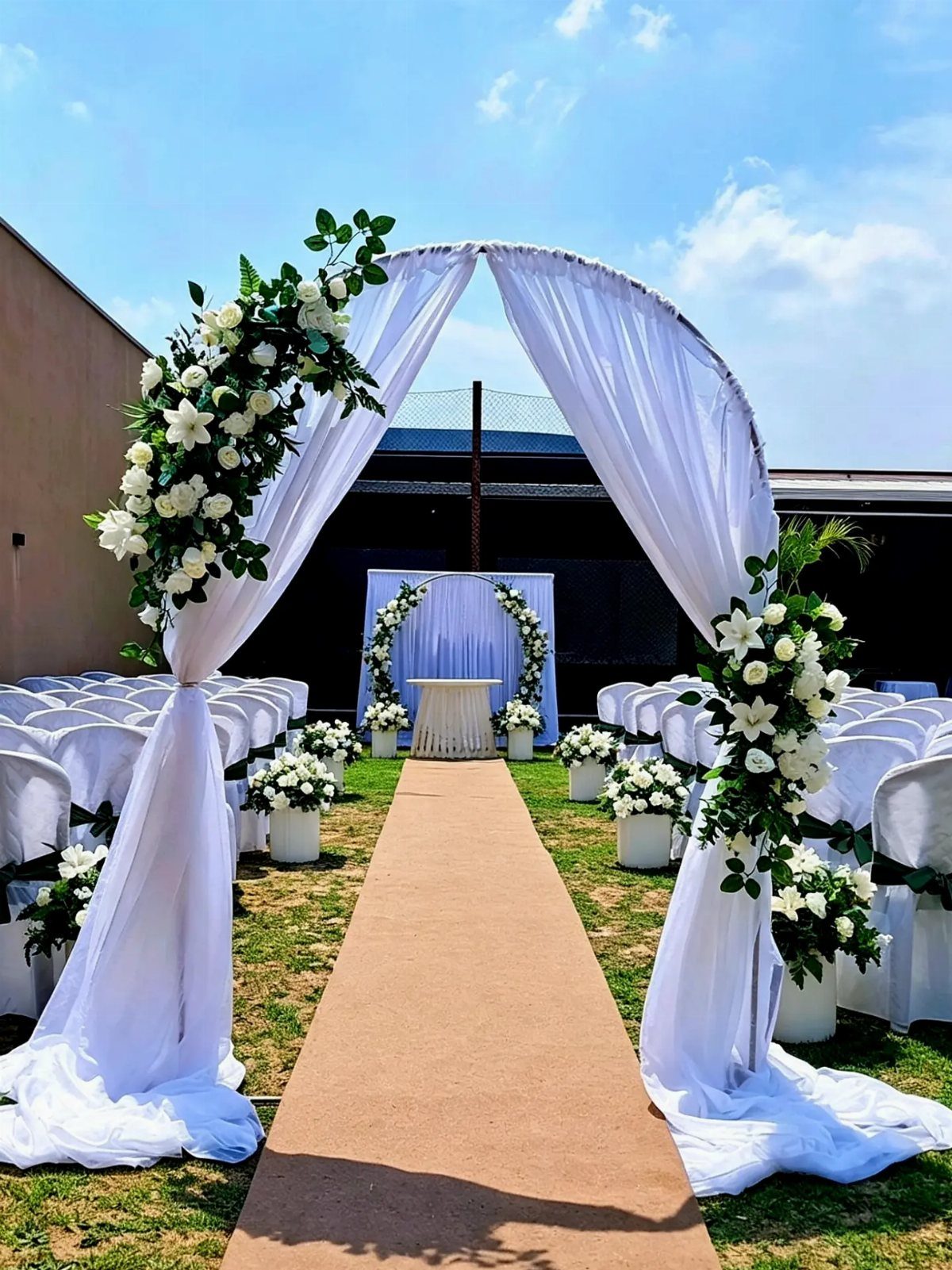 10 Outdoor Wedding Aisle Decor Ideas with Photos 2 A tan aisle runner leads through white chairs toward a decorated wedding altar outdoors.
