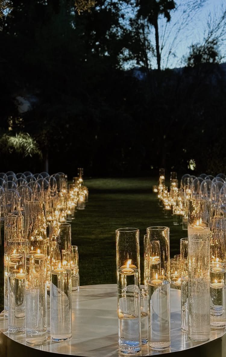 10 Outdoor Wedding Aisle Decor Ideas with Photos 3 Tall glass cylinders with floating lit candles lining a dark outdoor grassy aisle.