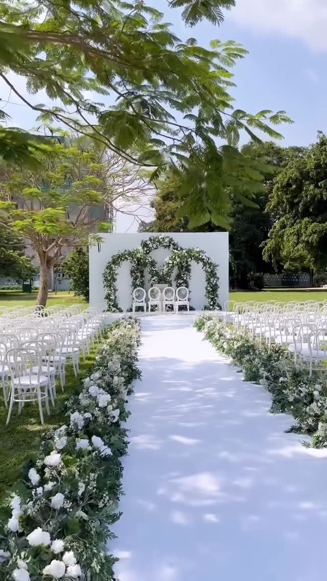 10 Outdoor Wedding Aisle Decor Ideas with Photos 8 White floral garlands and greenery lining a white wedding aisle runner outdoors.