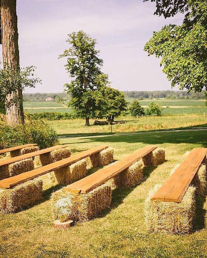 Wooden planks resting on rows of hay bales serving as rustic outdoor benches in a field.