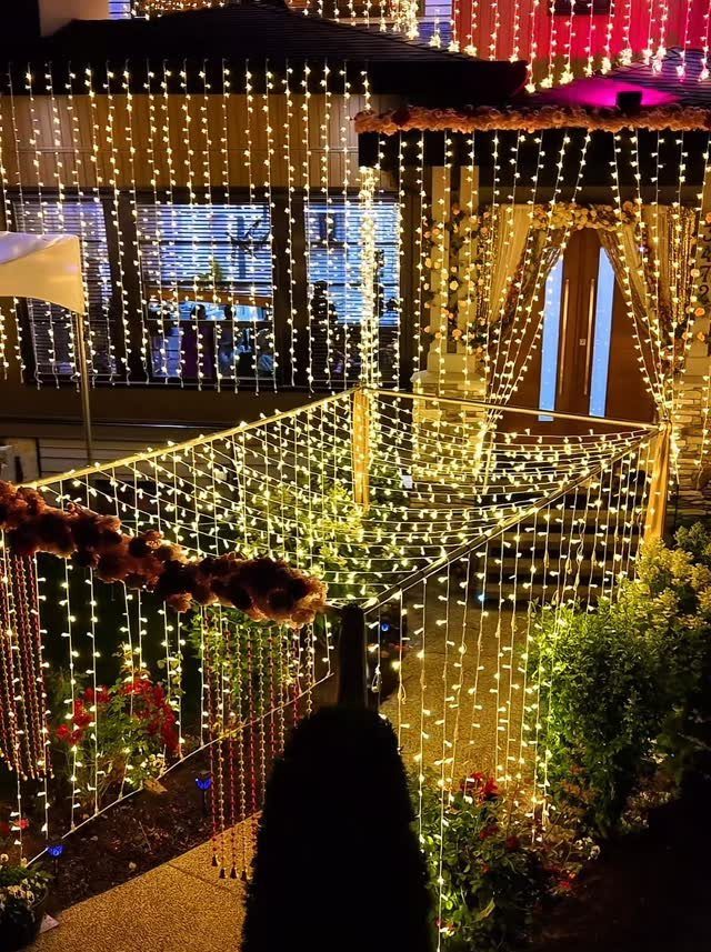 Vertical strands of warm white fairy lights hanging from a metal frame outdoors at night.