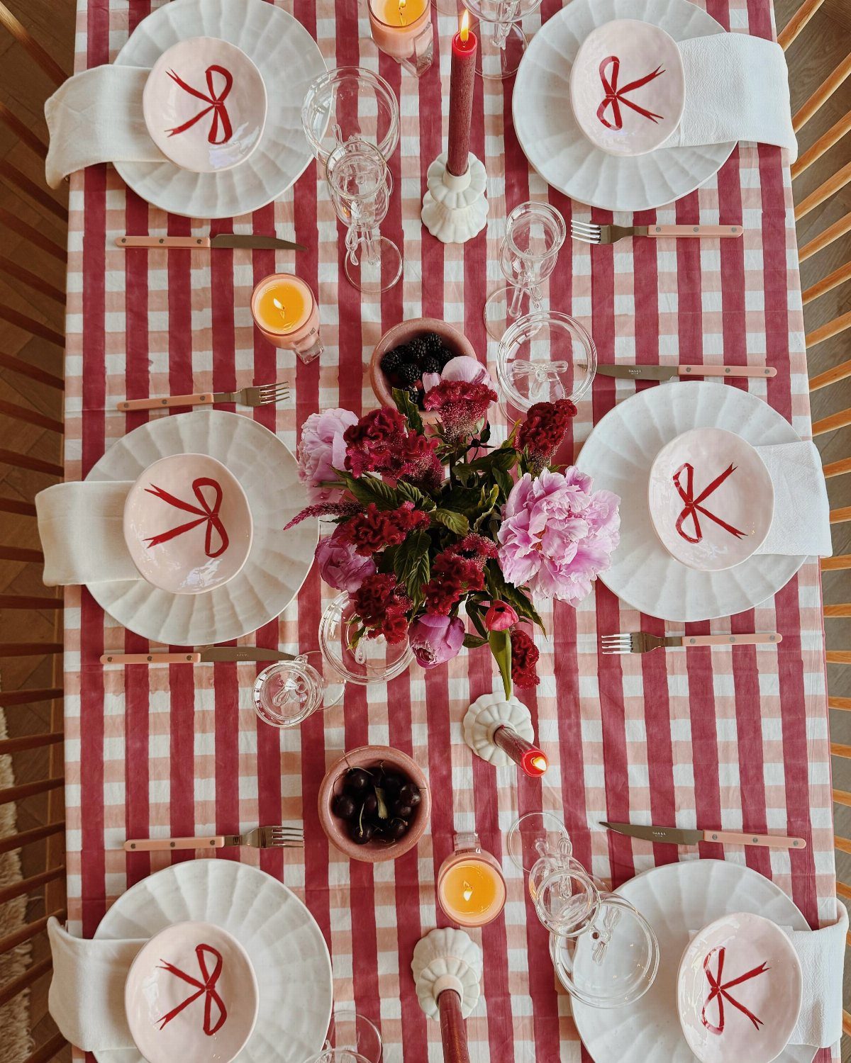 12 Ideas for a Red and White Wedding Theme 6 A dining table set with red and white checkered cloth, white plates, and pink floral centerpieces.