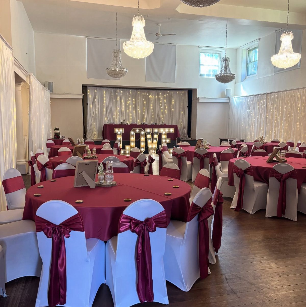 12 Ideas for a Red and White Wedding Theme 8 Wedding reception tables with burgundy linens and white chairs decorated with burgundy satin bows.