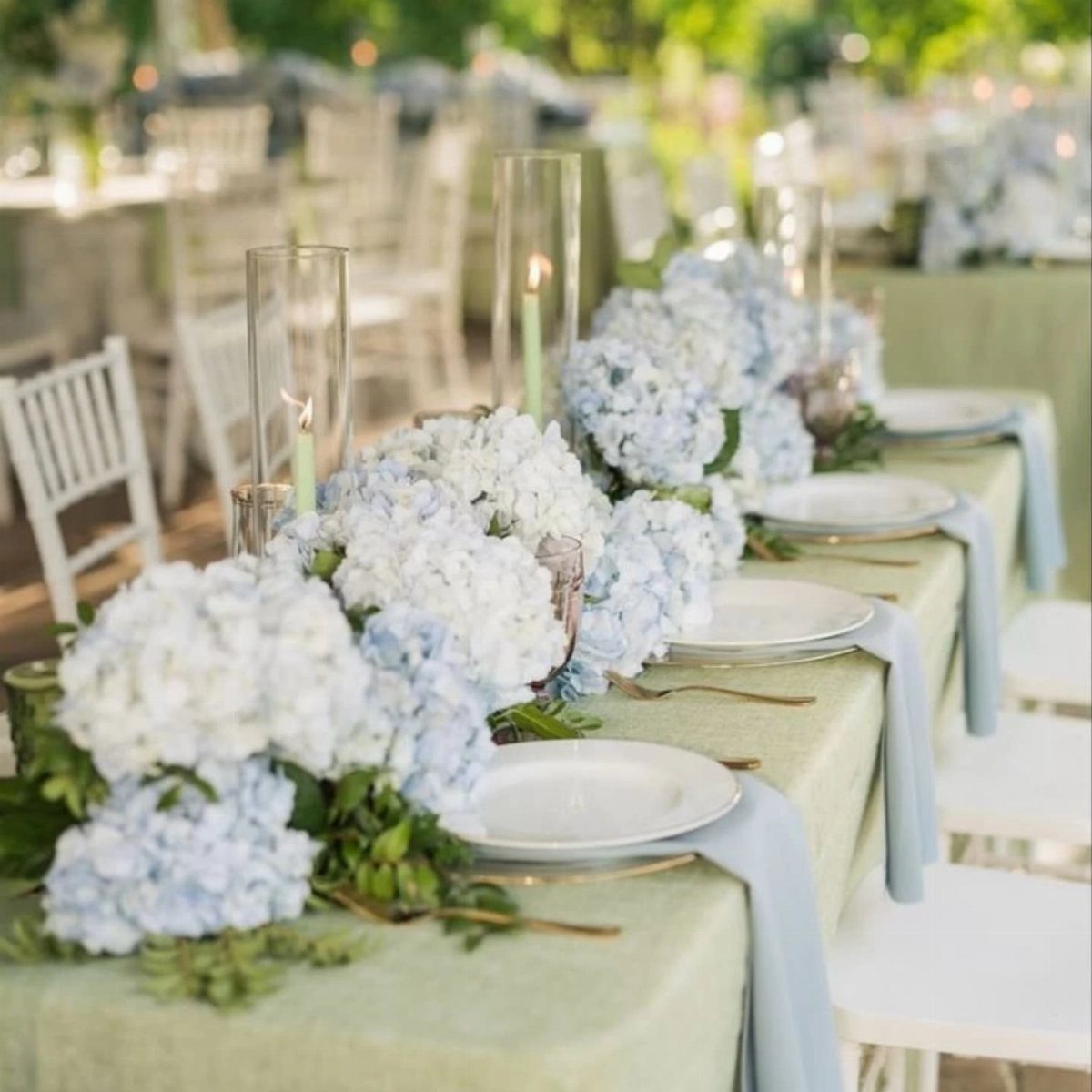 Light blue hydrangea centerpieces and napkins on a sage green wedding reception table.