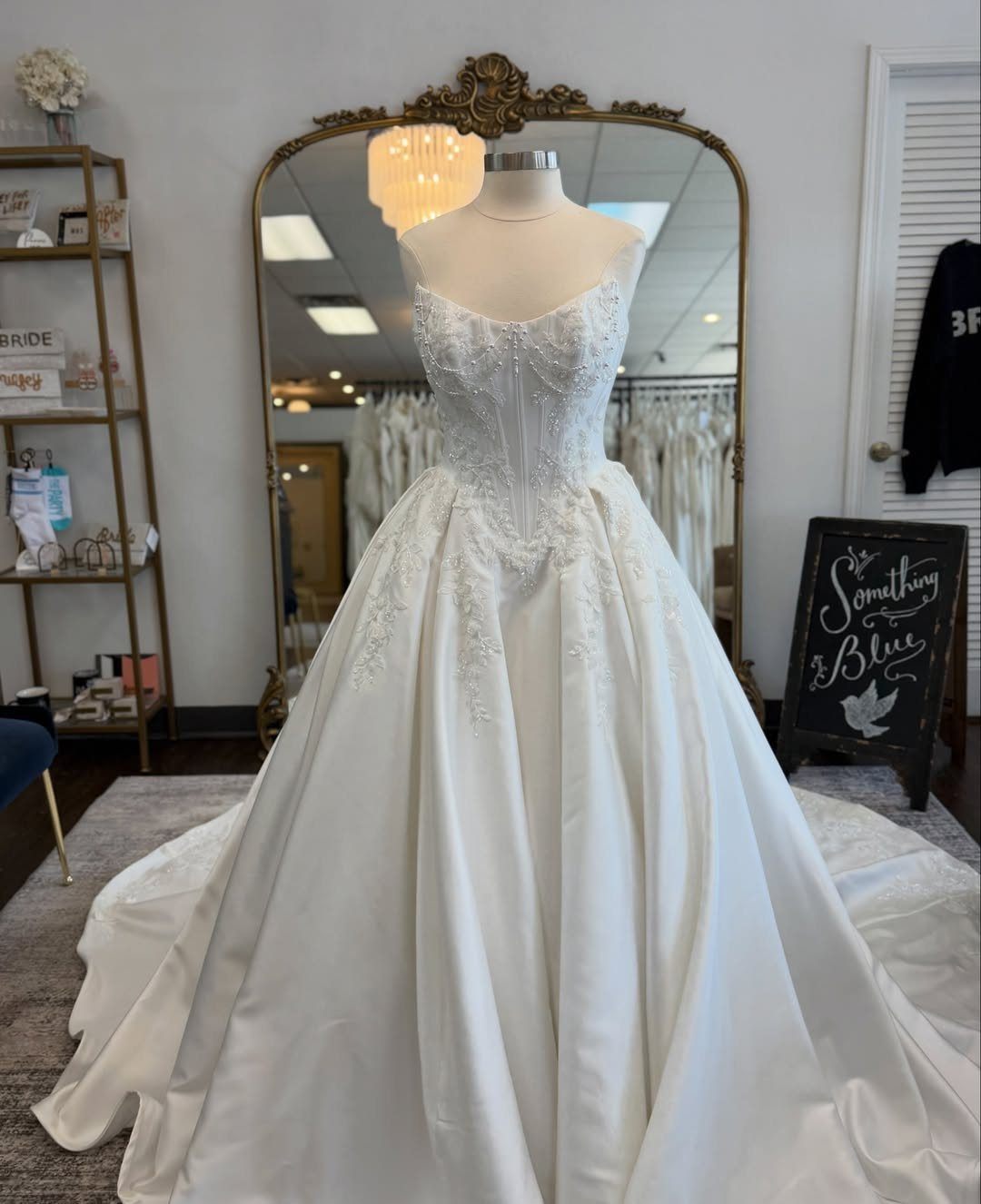 A strapless lace wedding dress with a full satin skirt displayed on a mannequin.