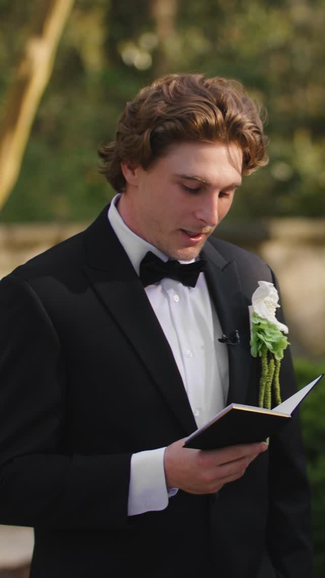 A man in a tuxedo reading from a small black book during a ceremony.