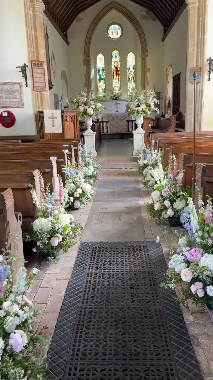 Wedding Decorations and Flowers: 8 Ideas for Ceremony to Reception 3 Floral arrangements line the aisle of a church leading toward the altar and stained glass windows.