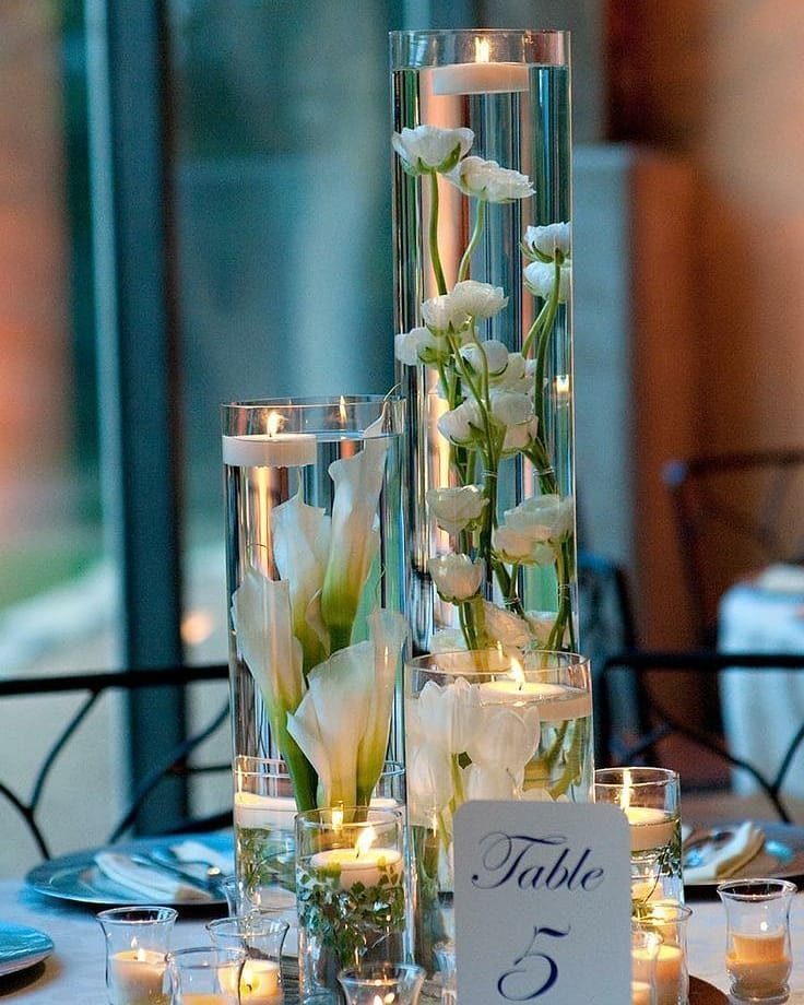 Wedding Decorations and Flowers: 8 Ideas for Ceremony to Reception 4 Tall glass vases with white flowers and floating candles arranged on a wedding reception table.