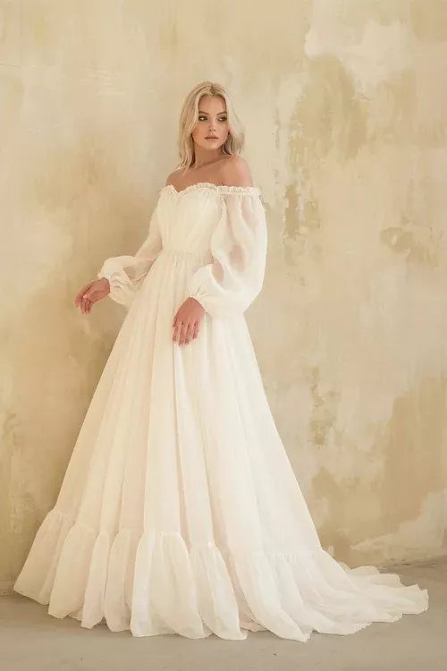 Wedding Dress Long Sleeve: 7 Styles From A-Line to Turtleneck 6 Blonde woman wearing a bohemian long sleeve white wedding dress with voluminous sheer sleeves.