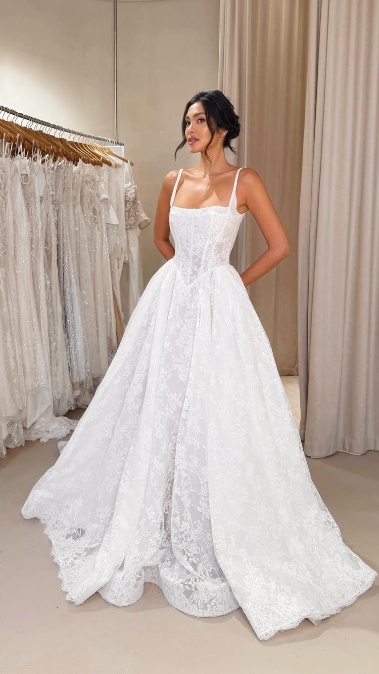 A woman wearing a white lace wedding dress with a corset bodice and full skirt.