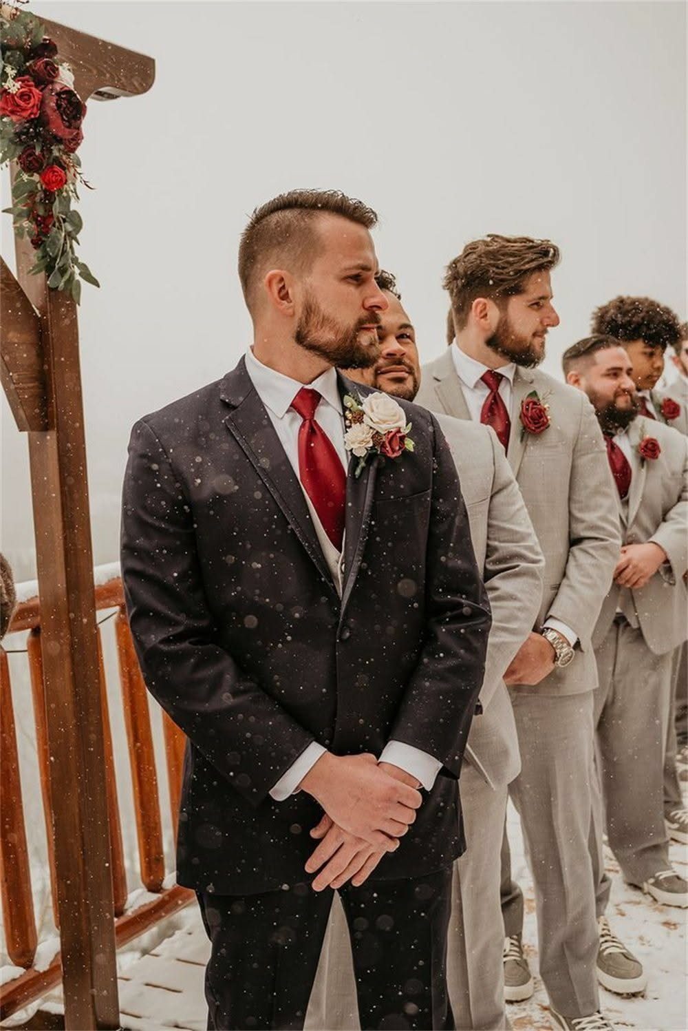 Men in suits standing outdoors, featuring a man in a dark suit wearing a burgundy tie.