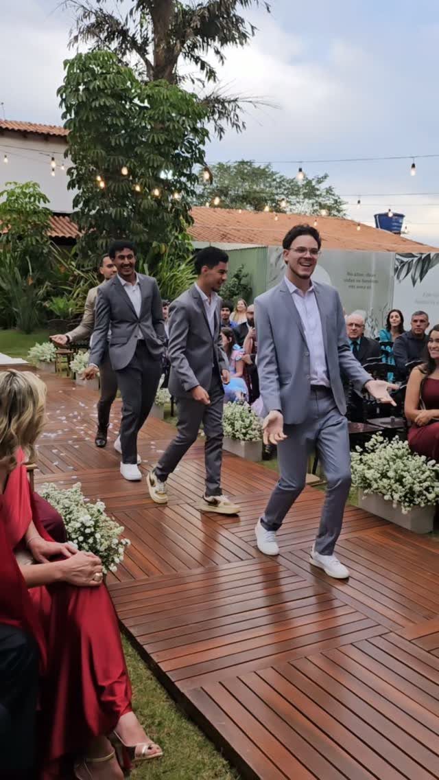 Three men in grey suits and white shirts walking happily on a wooden path outdoors.