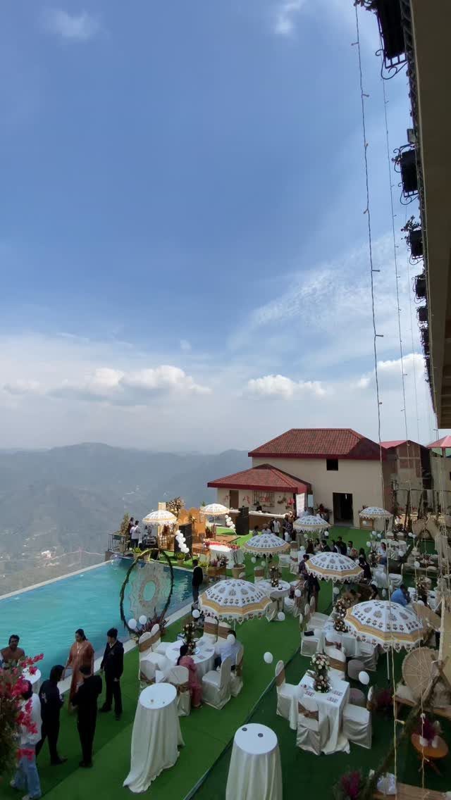 Wedding reception setup on a rooftop terrace with mountain views and a swimming pool.