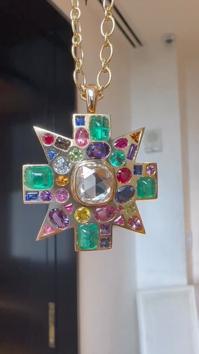 Gold star-shaped pendant necklace with a large clear center and many colorful gemstones.