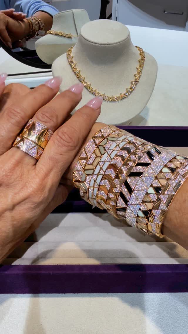 Hands adorned with a large geometric ring and a wide stack of sparkling diamond bracelets.