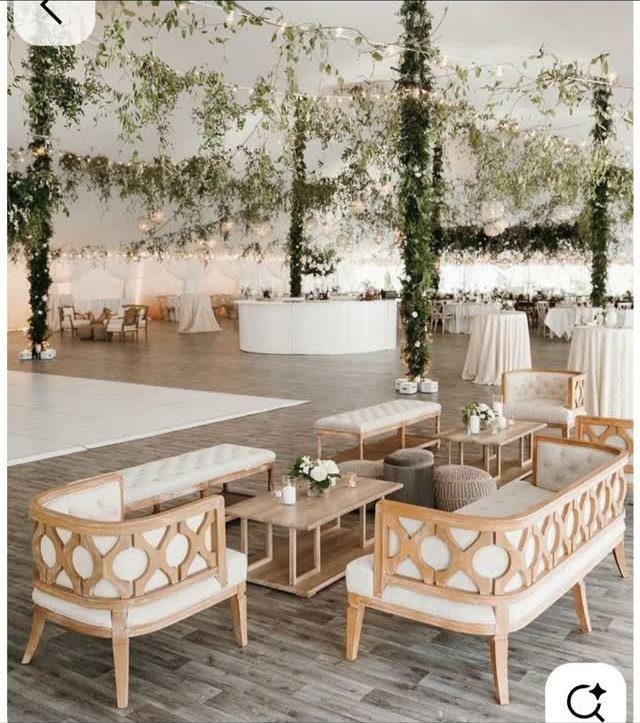 Cream upholstered sofas and wooden coffee tables arranged in a lounge area under a decorated tent ceiling.