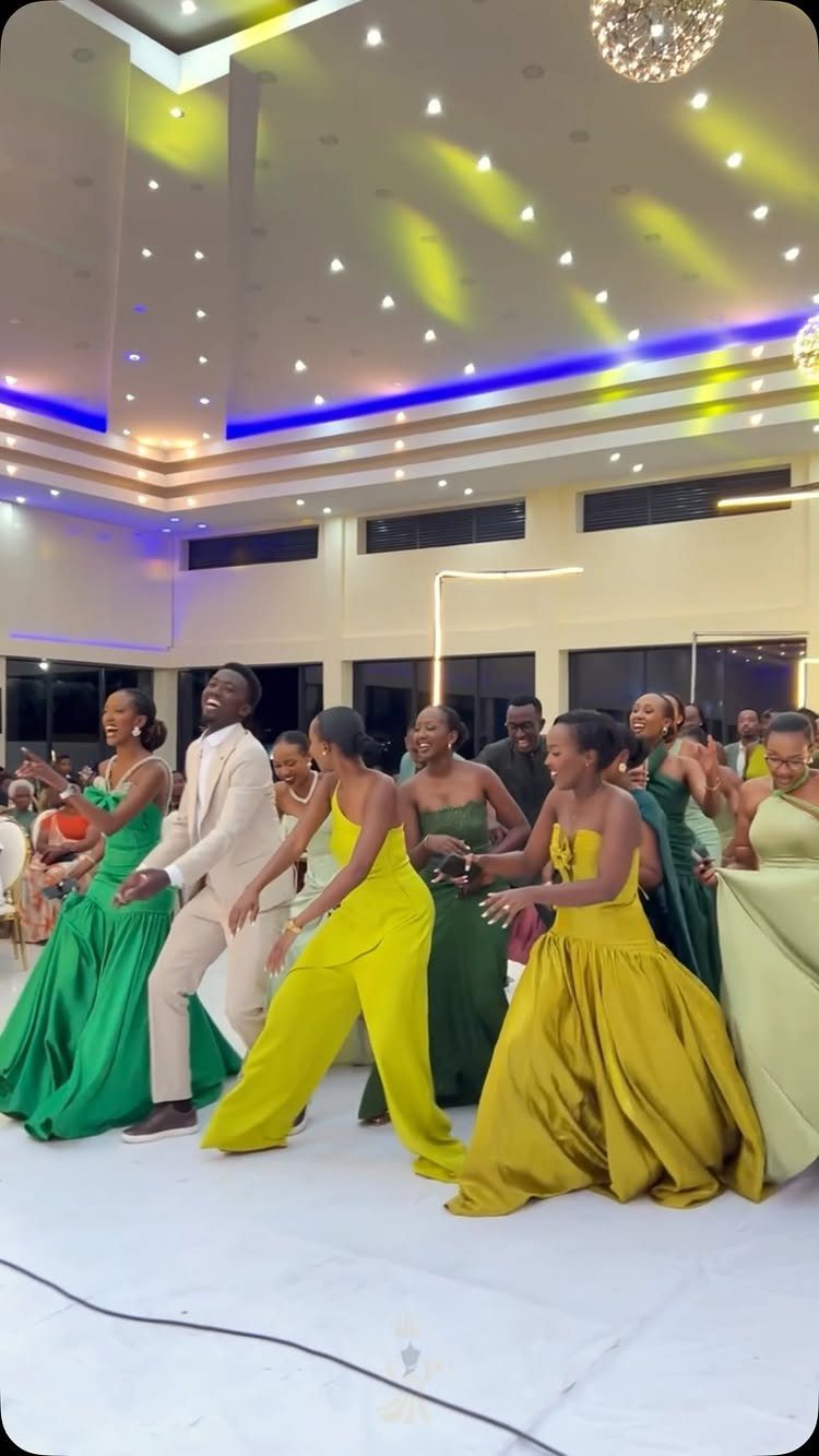 People in various shades of green formal dresses dancing in a brightly lit ballroom.