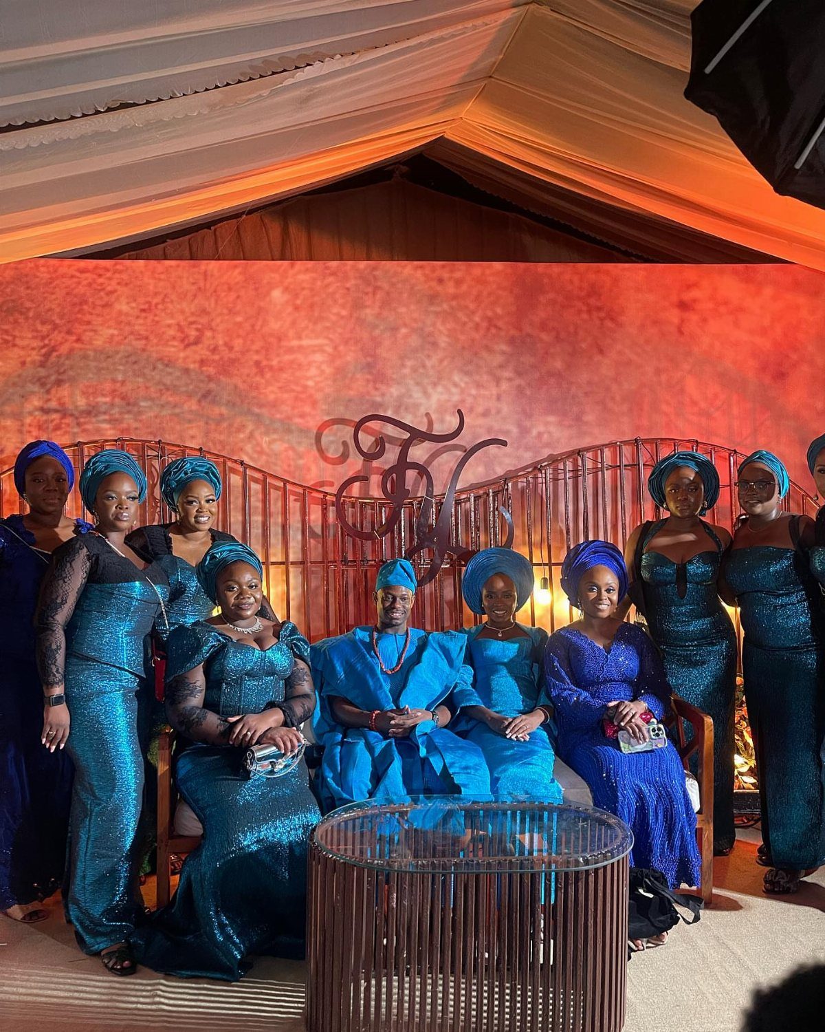 A group of women wearing shimmering teal formal dresses and matching headwraps posing together.
