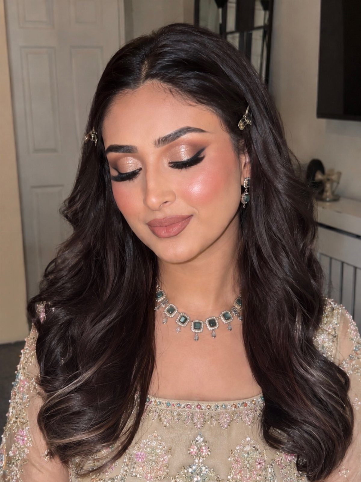 Woman with long wavy hair showcasing shimmering gold eyeshadow and soft glam makeup style.